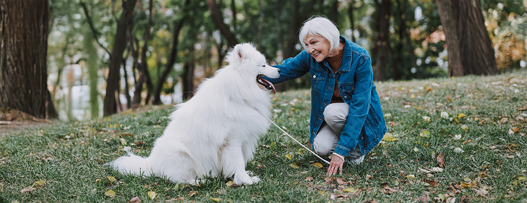 Image of senior woman patting her dog at a park